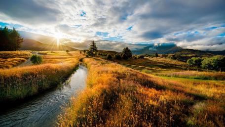Serene Fall Landscape with Brook and Cloudy Sky wallpaper