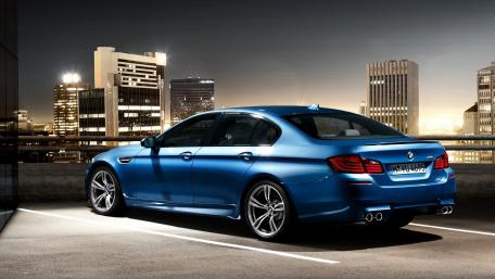 Sleek BMW M5 Against Urban Cityscape Night Skyline wallpaper