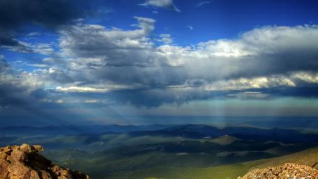 Sunlight Breaking Through Dramatic Clouds Over Mountains wallpaper