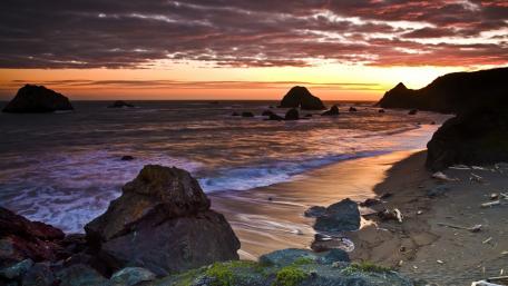 Serene Beach Sunset Over Rocky Coastline wallpaper