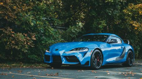 Sleek Blue Sports Car Surrounded by Nature Effortlessly Shines wallpaper