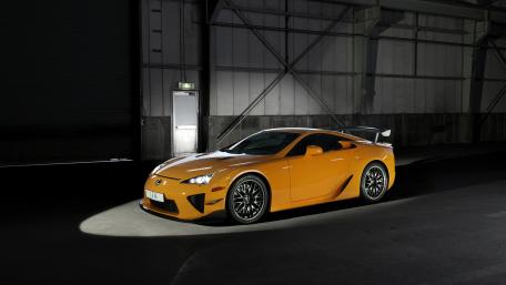 Sleek Orange Sports Car Spotlight wallpaper