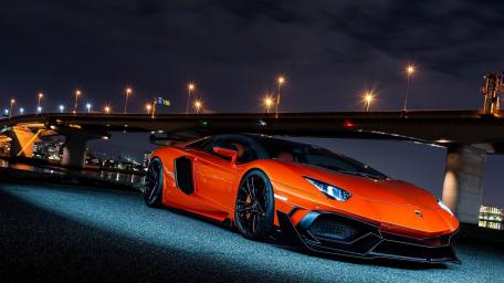 Sleek Orange Supercar Under City Lights wallpaper