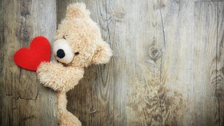 Teddy Bear Holding Red Heart on Wooden Surface wallpaper