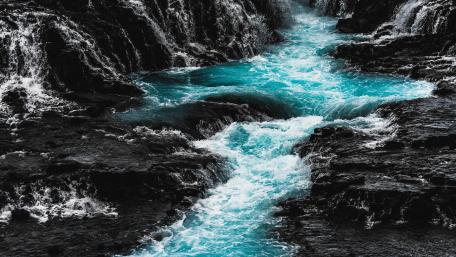 Turquoise Torrent Amidst Dark Rocks wallpaper