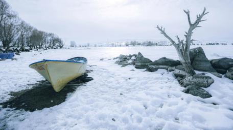 Serene Winter Landscape with Abandoned Boat and Snowy Shoreline wallpaper