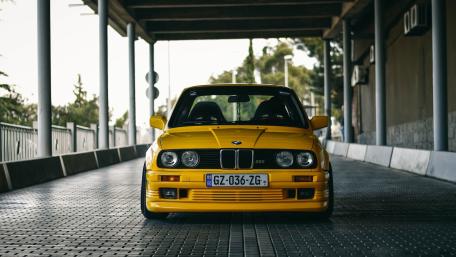 Yellow BMW E30 M3 in Urban Setting wallpaper