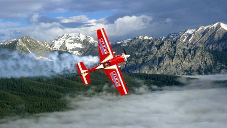 Thrilling Aerobatic Flight Over Majestic Peaks wallpaper