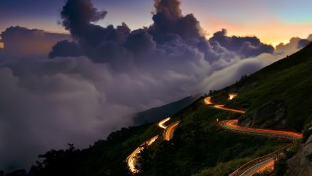 Winding Road Through Majestic Mountains at Dusk wallpaper