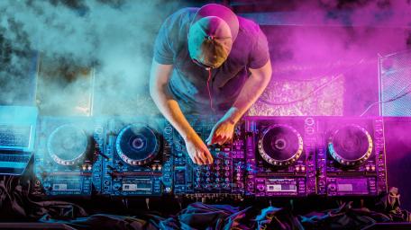 DJ in Action Amid Vibrant Lights and Smoke wallpaper