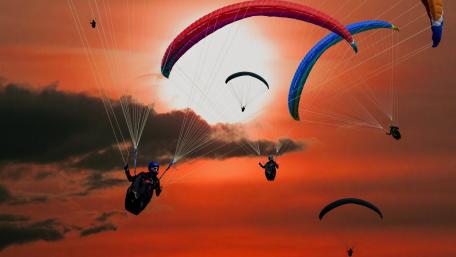 Paragliders Soar Against a Fiery Sunset Sky wallpaper