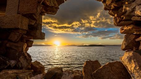 Coastal Sunset Through Ancient Ruins wallpaper