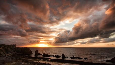 Serene Sunset Over a Cloudy Shoreline wallpaper