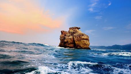 Majestic Rock Formation Amidst Ocean Waves wallpaper