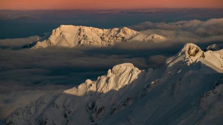 Sunlit Winter Peaks Above a Sea of Clouds 4K Wallpaper wallpaper