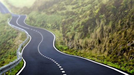 Winding Mountain Highway Through Misty Green Hills wallpaper