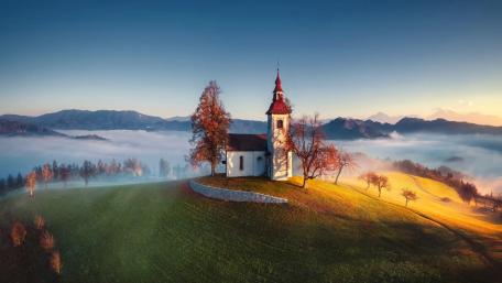 Misty Sunrise Over Saint Thomas Church in the Slovenian Alps wallpaper