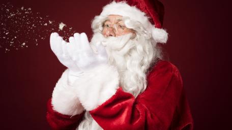 Santa Claus Blowing Snowflakes on Deep Red Christmas Background wallpaper