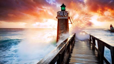 Sunset Lighthouse on Stormy Pier with Exploding Sea Spray wallpaper