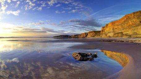 Golden Hour Sea Cliffs Reflecting on a Quiet Coastal Shore wallpaper