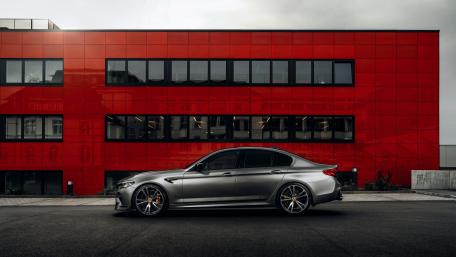 BMW M5 Side Profile Against Bold Red Modern Architecture wallpaper