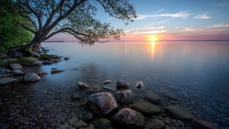 Sunset Serenity Over Rocky Lakeshore Horizon wallpaper