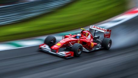 Formula 1 Red Race Car Blazing Through a High Speed Corner wallpaper