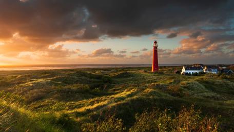 Sunset Over Schiermonnikoog Red Lighthouse And Coastal Dunes wallpaper