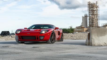 Red Ford GT Supercar in Industrial Landscape Ultra Sharp 8K Wallpaper wallpaper