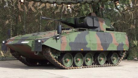 Camouflaged Armored Combat Vehicle Displayed Under Field Canopy wallpaper