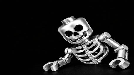 Shiny Lego Skeleton Strikes a Cheeky Pose on Deep Black wallpaper