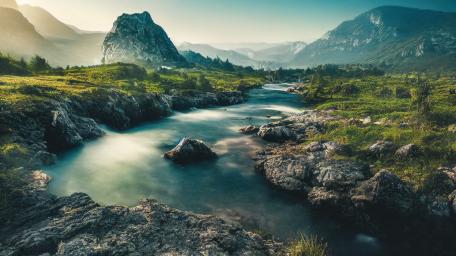 Emerald Highland River Winding Through Rocky Summits in Soft Morning Light wallpaper