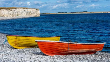 Colorful Boats Resting on a Pebble Beach by the Blue Sea wallpaper