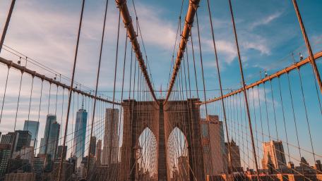 Sunlit Brooklyn Bridge Cables Framing Manhattan Skyline in New York City wallpaper