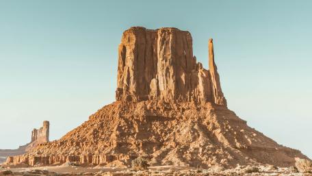 Sunlit Desert Butte Rising Above Monument Valley Plains wallpaper