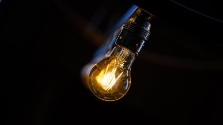 Glowing Edison Lightbulb in Deep Darkness Black Background 5K wallpaper
