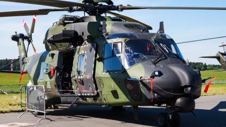 Camouflaged Military Helicopter on Airfield Tarmac Under Clear Blue Skies wallpaper