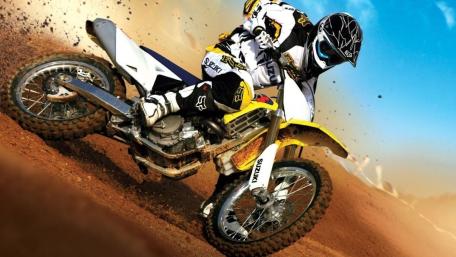 Suzuki Motocross Rider Carving a Dirt Berm in Full Speed wallpaper