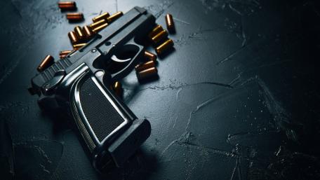Tactical Handgun and Scattered Bullets on Dark Steel Surface wallpaper