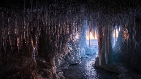 Sunlit Icicle Cave on Frozen Lake Baikal Shoreline wallpaper