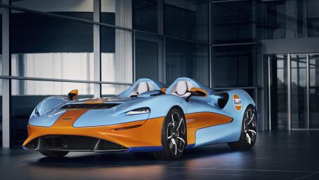 McLaren Elva Gulf Livery Supercar in Sleek Modern Showroom wallpaper