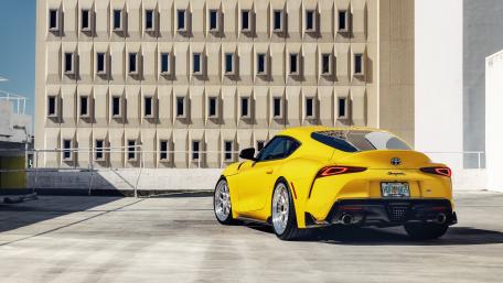 Sunlit Yellow Toyota Supra Supercar in Modern Concrete Cityscape wallpaper