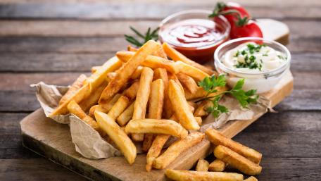 Golden French Fries with Dipping Sauces on Rustic Wooden Table wallpaper