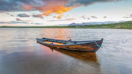 Solitary Weathered Boat Drifting on Calm Lake at Sunset in 4K wallpaper
