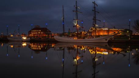 Meridianas Tall Ship Glowing Over the Danė River Reflection at Night wallpaper