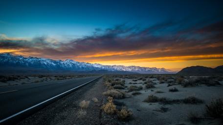 Endless Desert Highway at Dusk Beneath Snowy Mountains wallpaper
