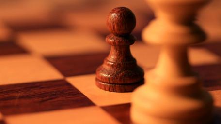 Focused Pawn on a Sunlit Chessboard of Strategic Tension wallpaper