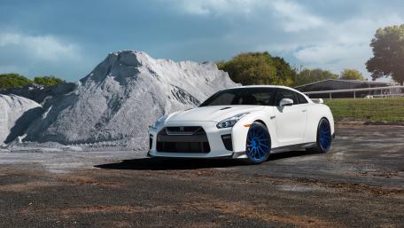 White Nissan GT-R with Blue Wheels in Dramatic Industrial Landscape wallpaper