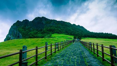 Pathway to Seongsan Ilchulbong Under Dramatic Jeju Skies wallpaper