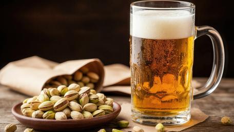 Golden Lager and Pistachio Snack Still Life on Rustic Tabletop wallpaper
